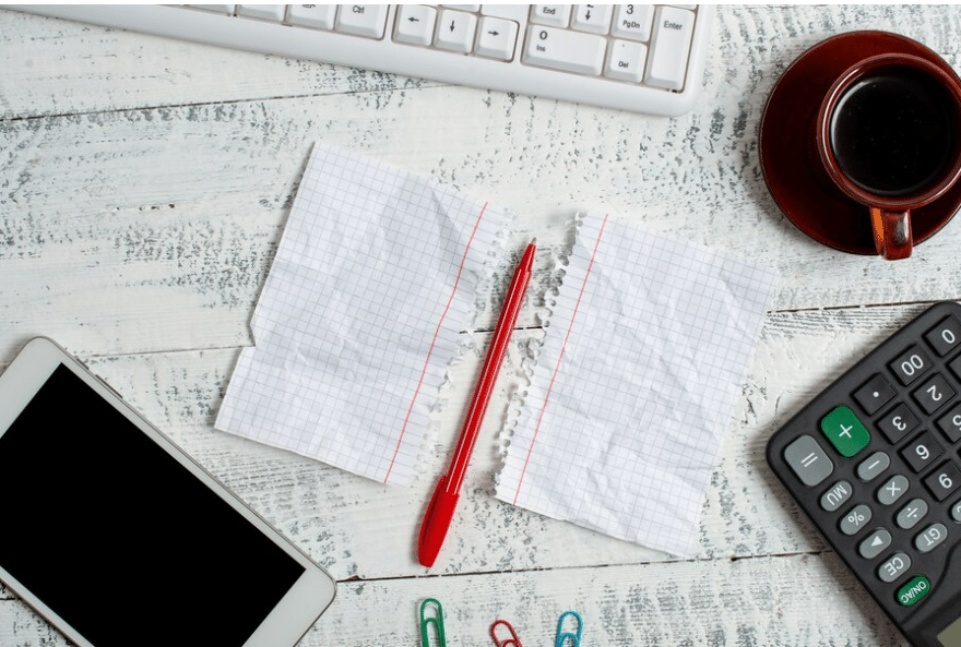 Stack of past papers with a red pen and calculator on top, representing the use of past papers for exam practice and time management